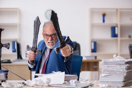 Old male employee unhappy with excessive work in the officeの写真素材