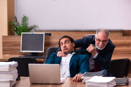 Old male employer and young male assistant in bullying conceptの写真素材