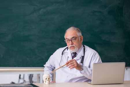 Old male doctor teacher in front of blackboardの写真素材