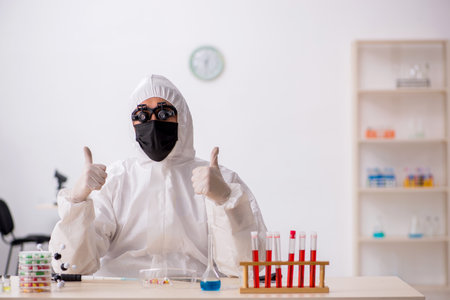 Young male chemist in drugs synthesis conceptの写真素材