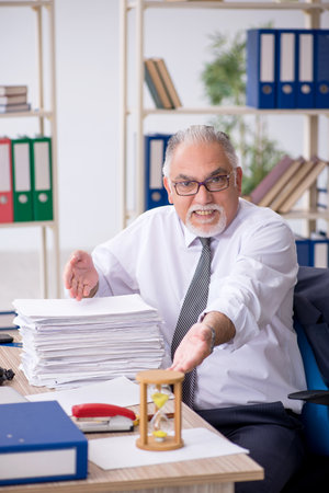 Old male employee in time management conceptの写真素材