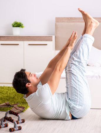 Young man doing morning routine in bedroomの写真素材