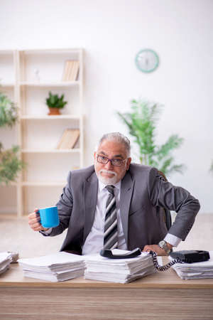 Old male employee and too much work in the officeの写真素材