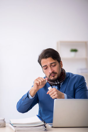Young male employee suffering at workplaceの写真素材