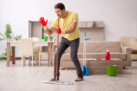 Young male contractor cleaning the houseの写真素材