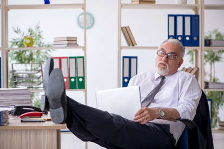 Old male employee and too much work in the officeの写真素材