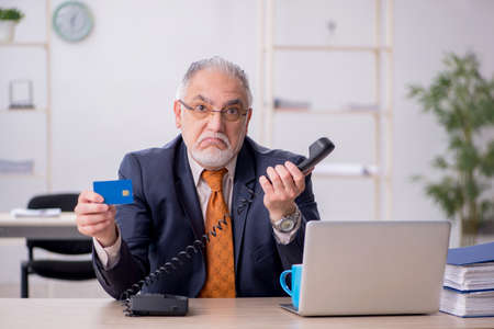 Old male employee holding credit card in the officeの写真素材