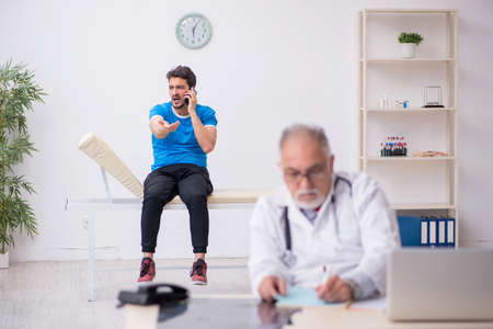 Young male patient visiting old male doctorの写真素材
