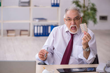 Old drug addicted employee sitting in the officeの写真素材