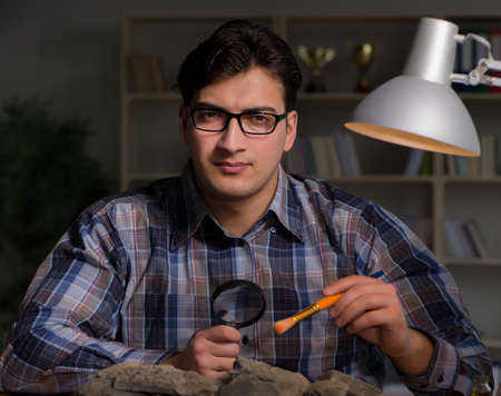 Archeologist working late night in officeの写真素材