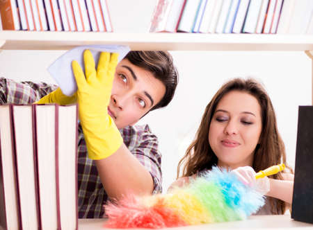 Wife and husband cleaning dust from bookshelf