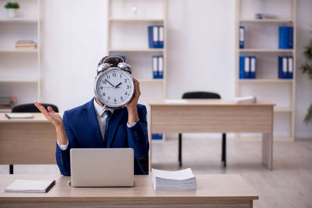 Young male employee in time management conceptの写真素材