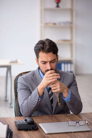 Young male employee unhappy with excessive work in the officeの写真素材