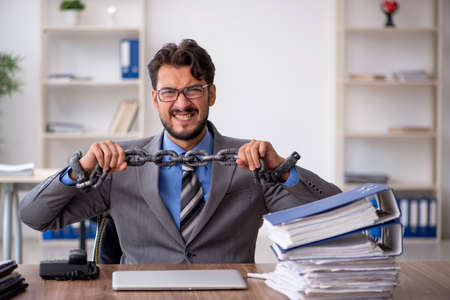 Young chained male employee sitting in the officeの写真素材