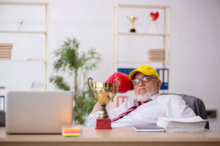 Old male employee boxer being awarded with golden cupの写真素材