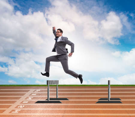 Businessman jumping over barriers in business conceptの写真素材