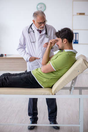Young male patient visiting old male doctorの写真素材