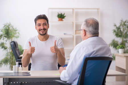 Young male patient visiting old male doctorの写真素材