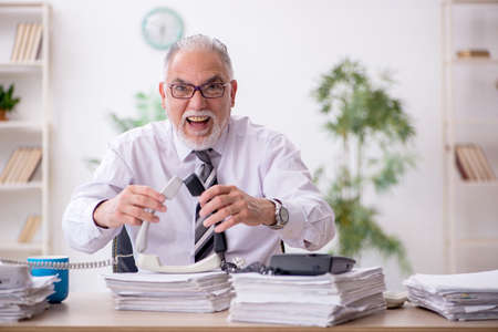 Old male employee and too much work in the officeの写真素材