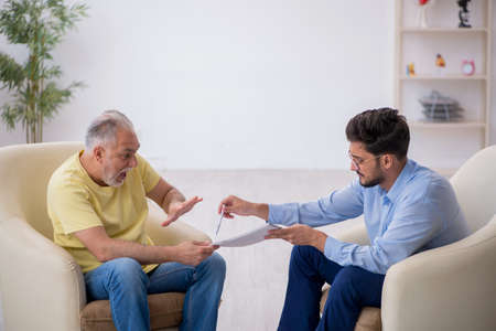 Old man visiting young male psychotherapistの写真素材