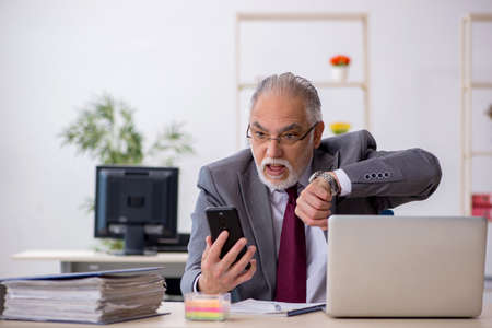 Old male employee sitting in the officeの写真素材