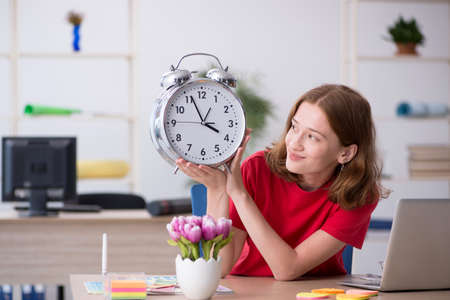 Young female designer in time management conceptの写真素材