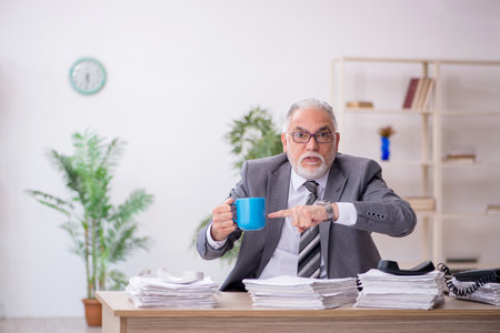 Old male employee and too much work in the officeの写真素材