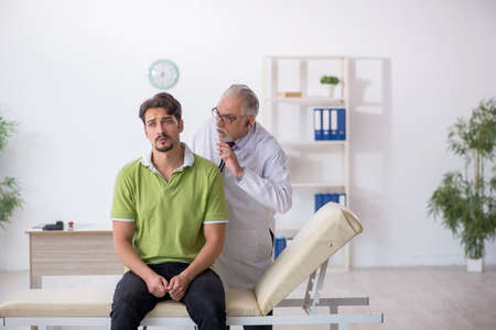 Young male patient visiting old male doctorの写真素材