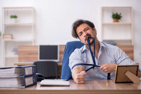 Young male drug addicted employee at workplace