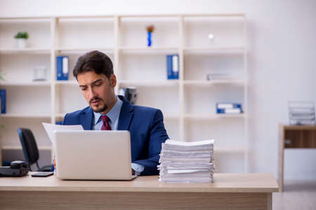 Young businessman employee and too much work in the officeの写真素材