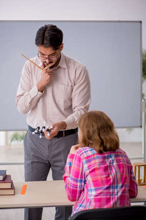 Young male teacher and redhead girl in the classroomの写真素材