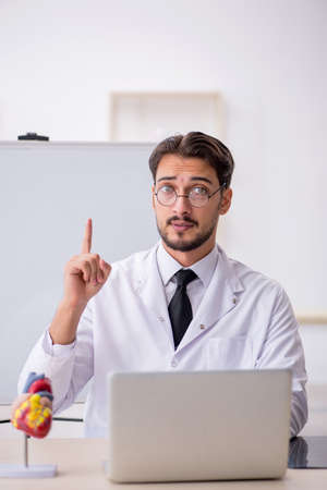 Young male doctor cardiologist sitting in the classroomの写真素材