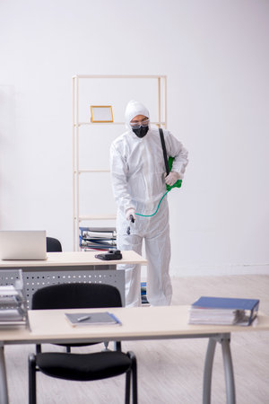Young male contractor disinfecting office during pandemicの写真素材