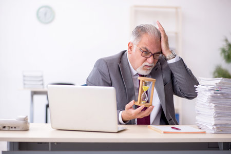 Old male employee in time management concept