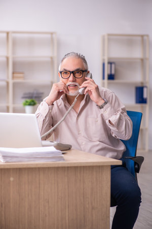 Old male employee working at workplaceの写真素材