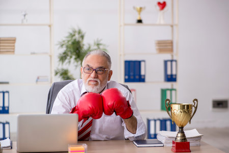 Old male employee boxer being awarded with golden cupの写真素材