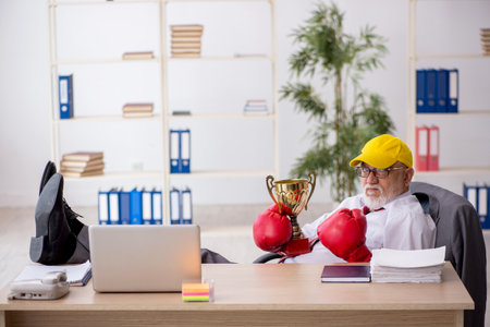 Old male employee boxer being awarded with golden cupの写真素材