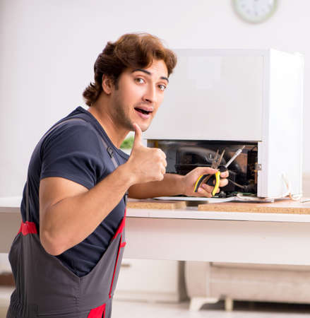 The young handsome contractor repairing fridgeの写真素材