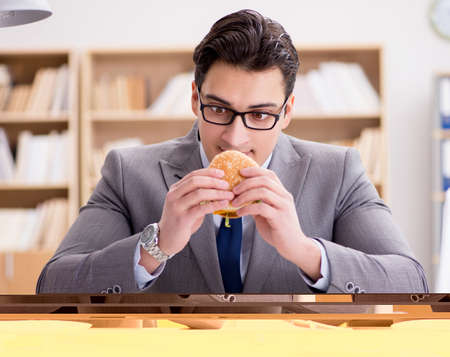 Hungry funny businessman eating junk food sandwichの写真素材