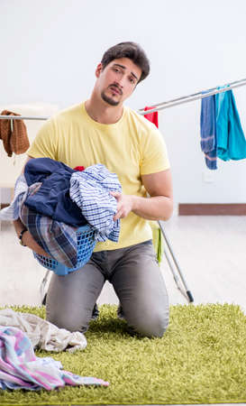 Handsome man husband doing laundering at homeの写真素材