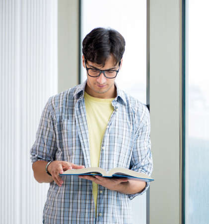 The young handsome student standing at the windowの写真素材