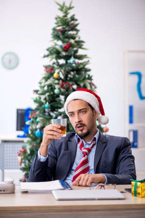 Young male employee celebrating Christmas at workplaceの写真素材