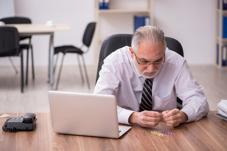 Aged male employee suffering at workplaceの写真素材