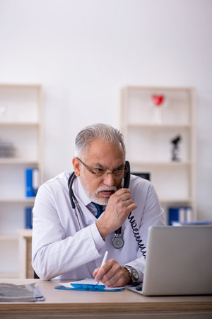 Old male doctor in telemedicine conceptの写真素材
