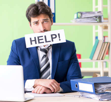 Businessman unhappy with excessive work sitting in the officeの写真素材
