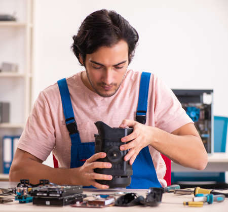 The young male contractor repairing computerの写真素材