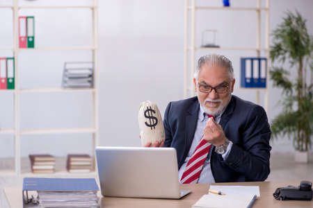 Old male employee in remuneration concept at workplaceの写真素材