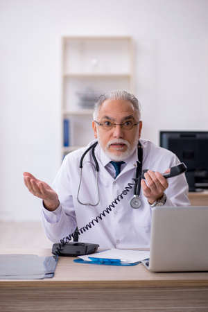 Old male doctor in telemedicine concept