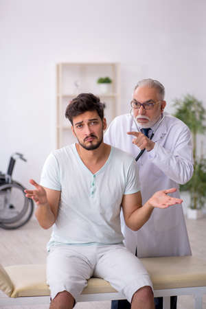Young male patient visiting old male doctorの写真素材