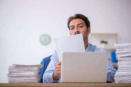 Young male employee and too much work in the office